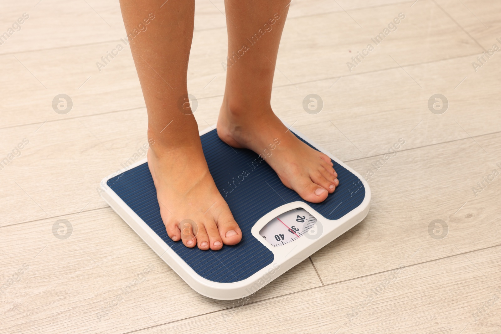 Photo of Little boy standing on scales indoors, closeup