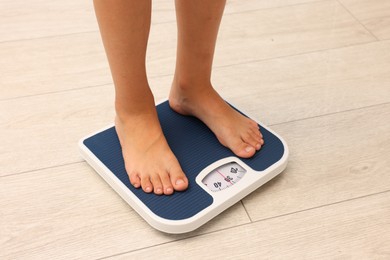 Photo of Little boy standing on scales indoors, closeup