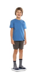 Photo of Little boy standing on scales against white background