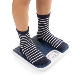 Photo of Little boy standing on scales against white background, closeup