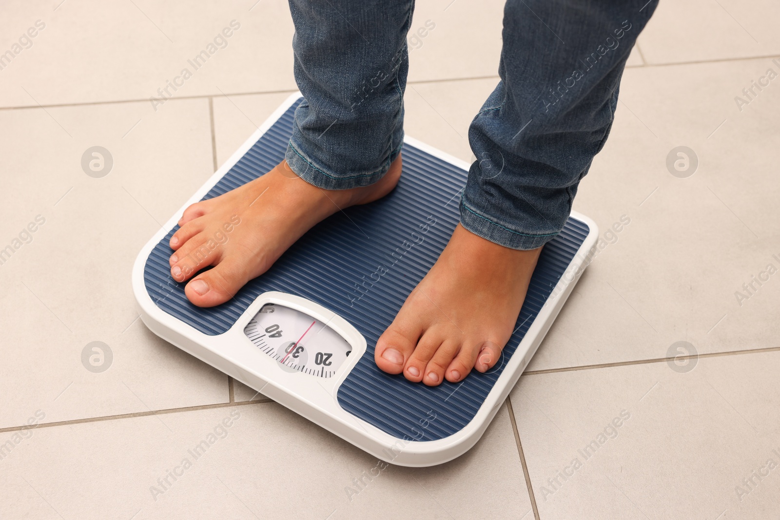 Photo of Little boy standing on scales indoors, above view