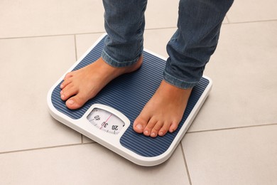 Photo of Little boy standing on scales indoors, above view