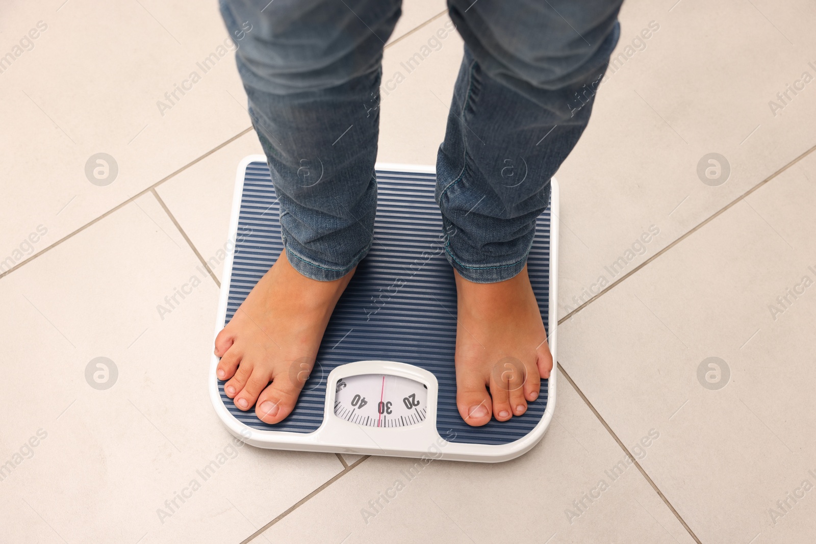 Photo of Little boy standing on scales indoors, above view