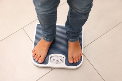 Photo of Little boy standing on scales indoors, above view