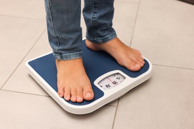 Photo of Little boy standing on scales indoors, closeup