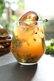Photo of Tasty passion fruit drink in glass on gray table, closeup