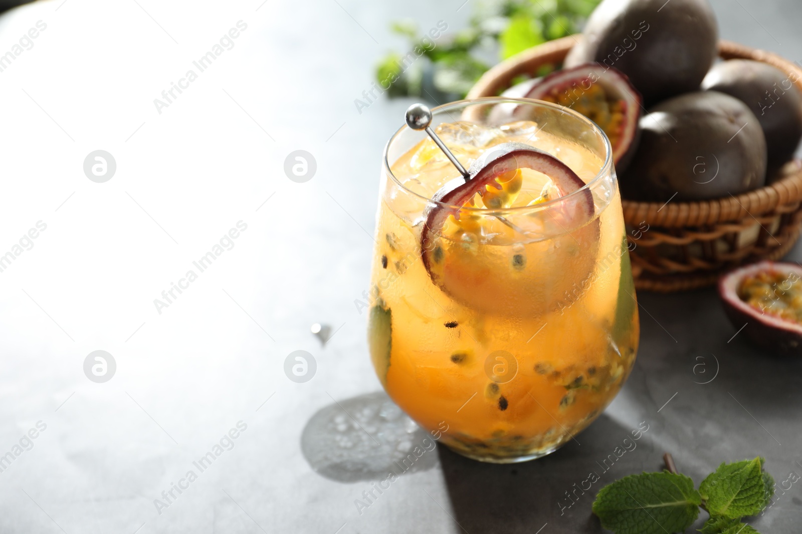 Tasty passion fruit drink in glass, fresh fruits and mint on gray table, closeup. Space for text Photo of Tasty passion fruit drink in glass, fresh fruits and mint on gray table, closeup. Space for text