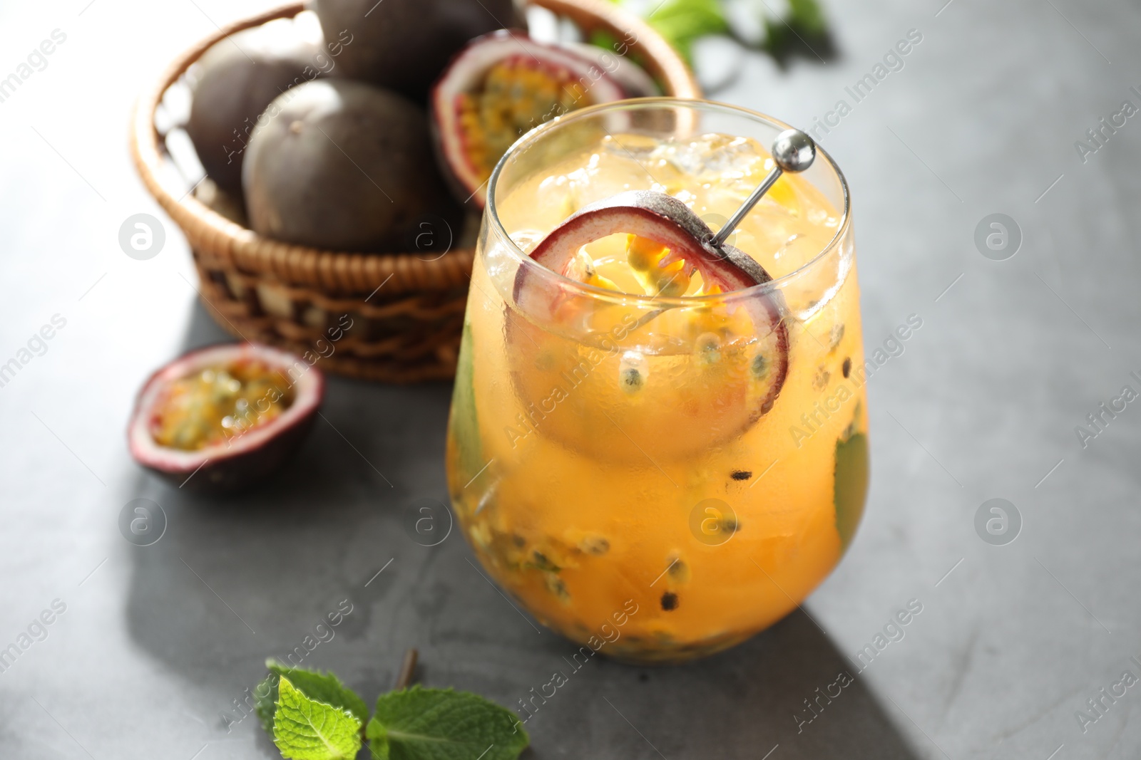 Tasty passion fruit drink in glass, fresh fruits and mint on gray table, closeup Photo of Tasty passion fruit drink in glass, fresh fruits and mint on gray table, closeup