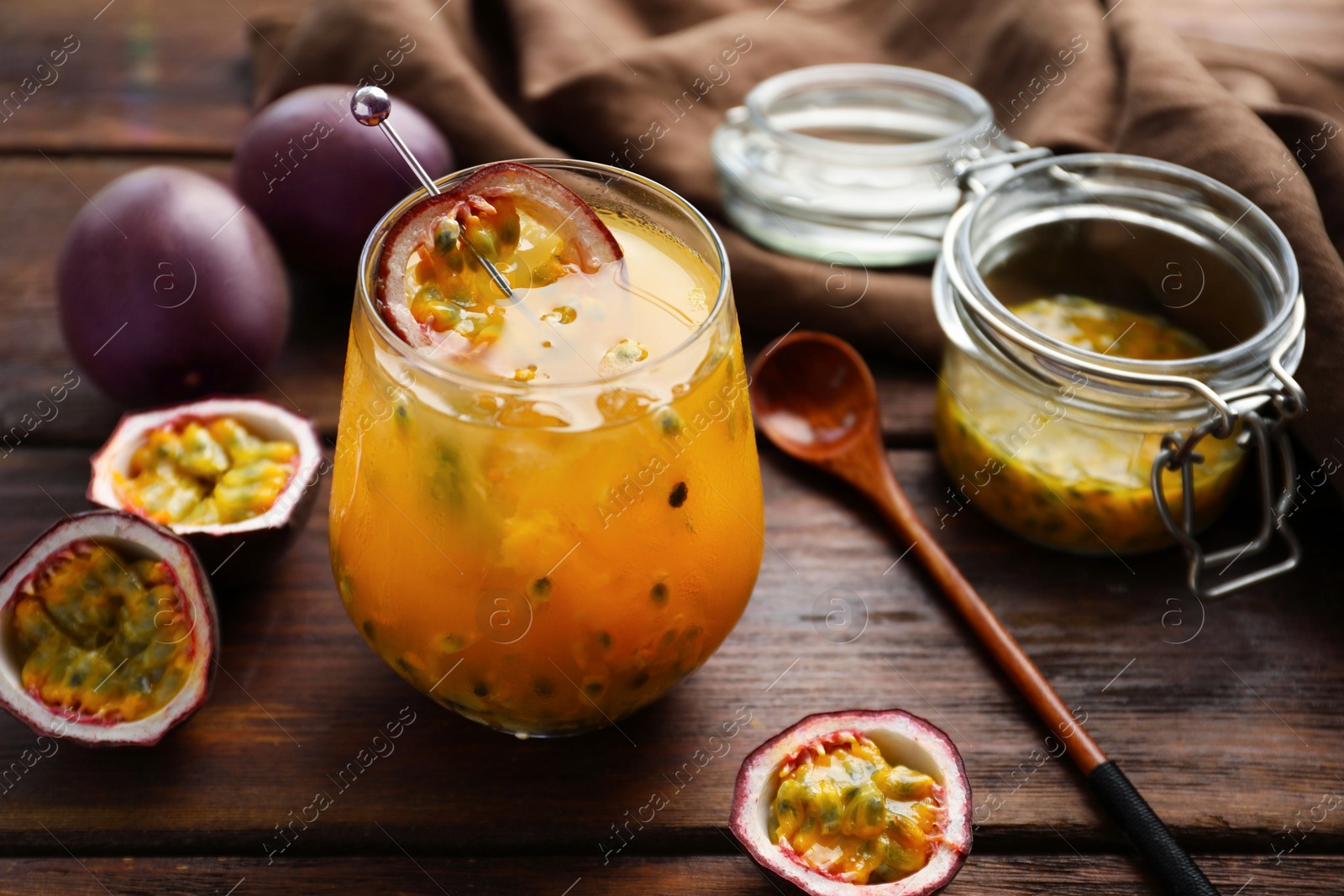 Tasty passion fruit drink in glass and fresh fruits on wooden table, closeup Photo of Tasty passion fruit drink in glass and fresh fruits on wooden table, closeup