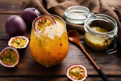 Photo of Tasty passion fruit drink in glass and fresh fruits on wooden table, closeup