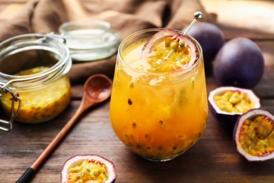 Photo of Tasty passion fruit drink in glass and fresh fruits on wooden table, closeup