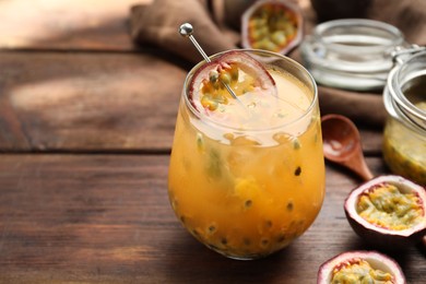 Photo of Tasty passion fruit drink in glass and fresh fruits on wooden table, closeup. Space for text