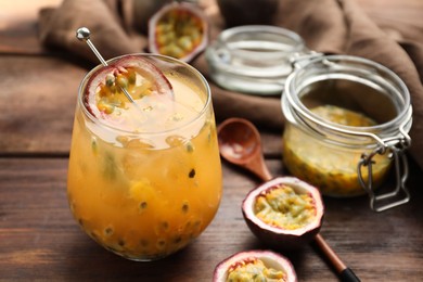Photo of Tasty passion fruit drink in glass and fresh fruits on wooden table, closeup