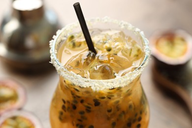 Photo of Tasty passion fruit drink in glass on table, closeup