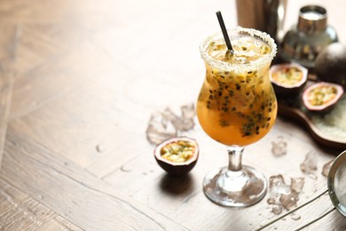 Photo of Tasty passion fruit drink in glass on table, closeup. Space for text