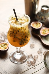 Photo of Tasty passion fruit drink in glass and fresh fruits on table, closeup