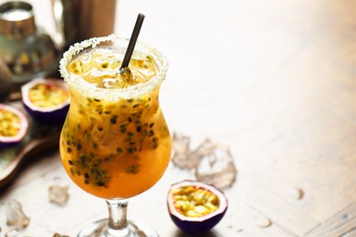 Photo of Tasty passion fruit drink in glass on table, closeup. Space for text