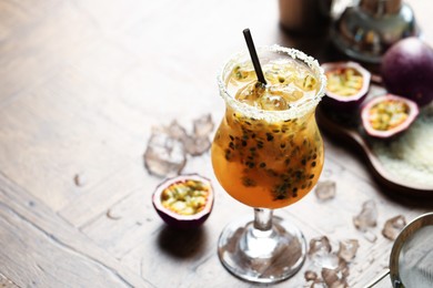Photo of Tasty passion fruit drink in glass on table, closeup. Space for text