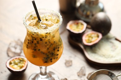 Photo of Tasty passion fruit drink in glass and fresh fruits on table, closeup