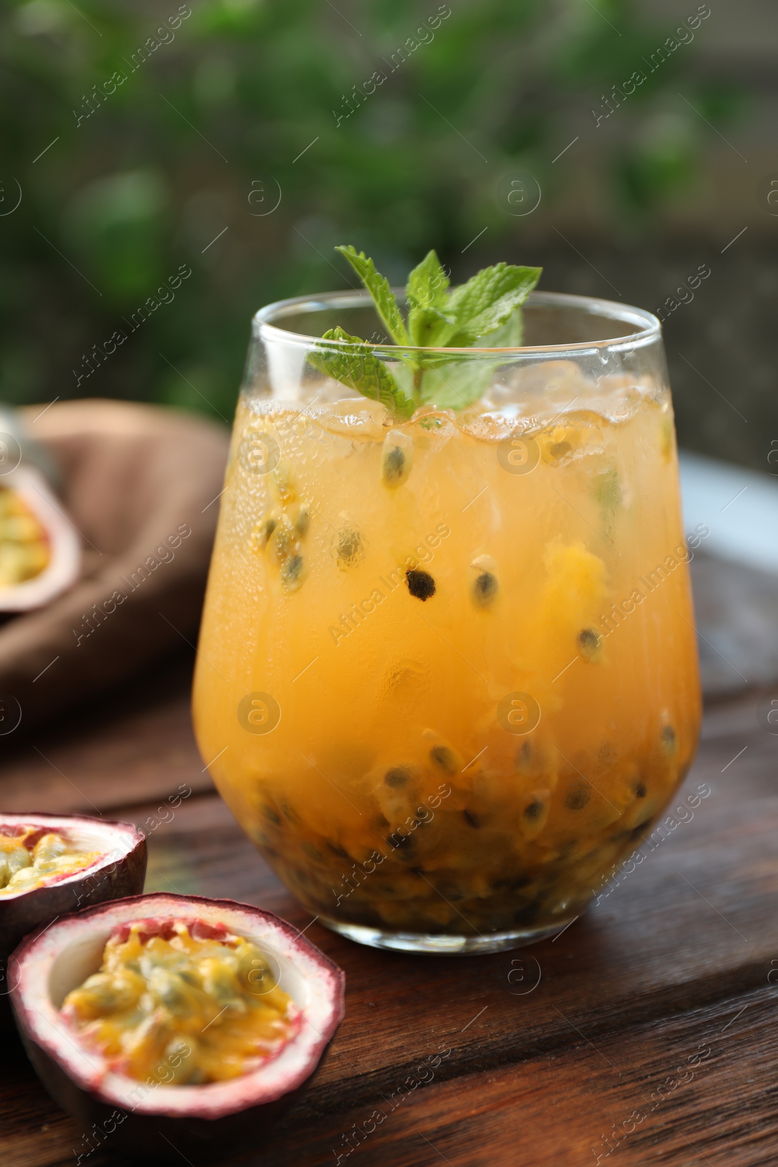 Tasty passion fruit drink with mint in glass and fresh fruits on wooden table, closeup Photo of Tasty passion fruit drink with mint in glass and fresh fruits on wooden table, closeup