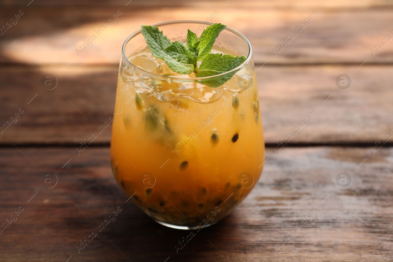 Tasty passion fruit drink with mint in glass on wooden table, closeup Photo of Tasty passion fruit drink with mint in glass on wooden table, closeup