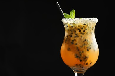 Photo of Tasty passion fruit drink with mint in glass against black background, closeup. Space for text