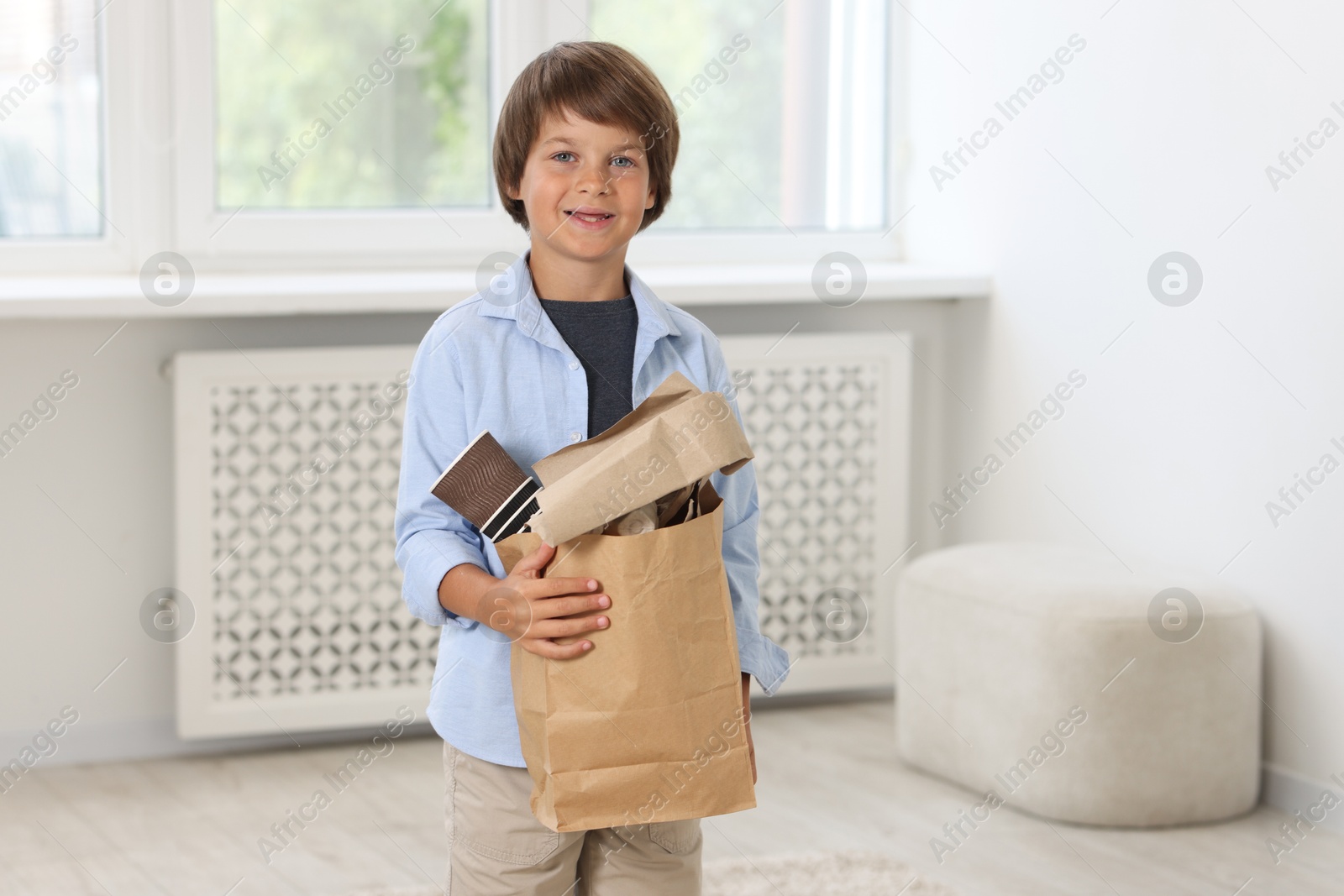 Recycling. Cute little boy with bag full of different waste paper at home Photo of Recycling. Cute little boy with bag full of different waste paper at home