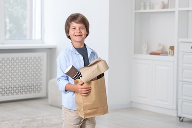 Photo of Recycling. Cute little boy with bag full of different waste paper at home, space for text