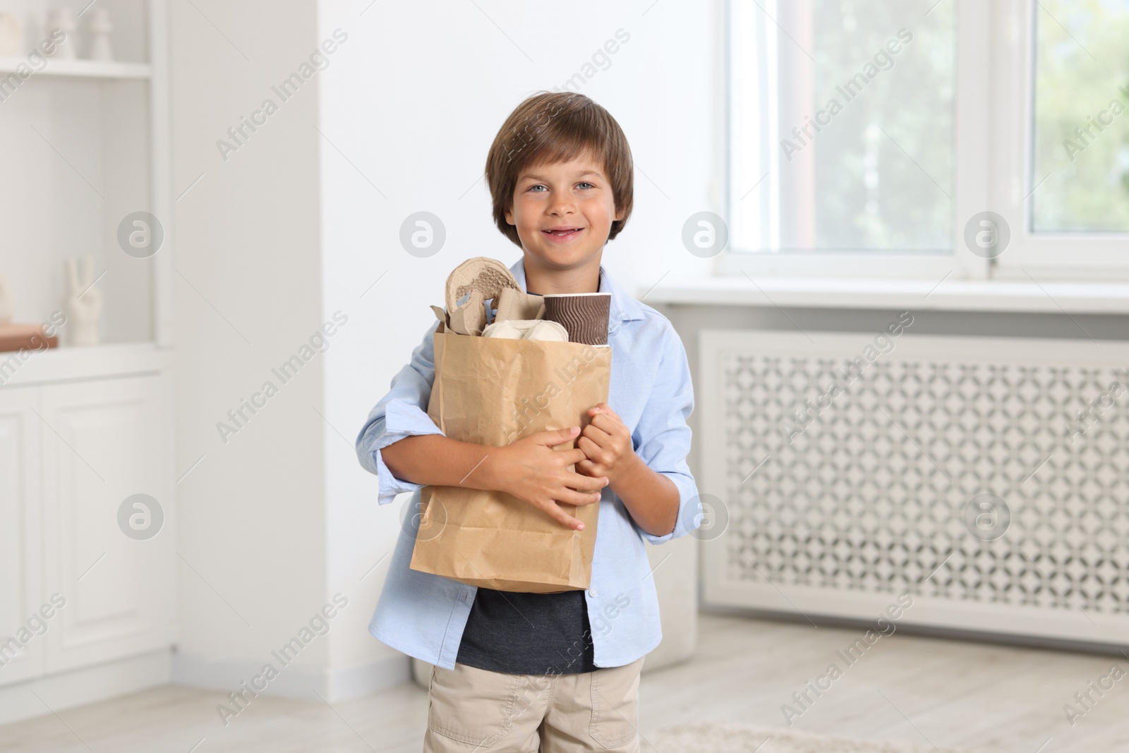 Recycling. Cute little boy with bag full of different waste paper at home Photo of Recycling. Cute little boy with bag full of different waste paper at home