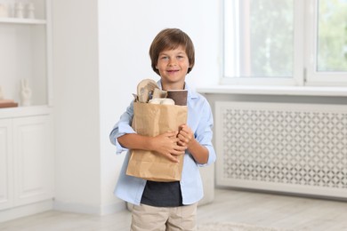 Photo of Recycling. Cute little boy with bag full of different waste paper at home