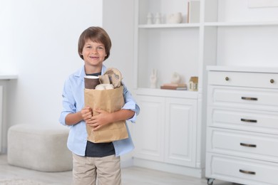 Photo of Recycling. Cute little boy with bag full of different waste paper at home, space for text