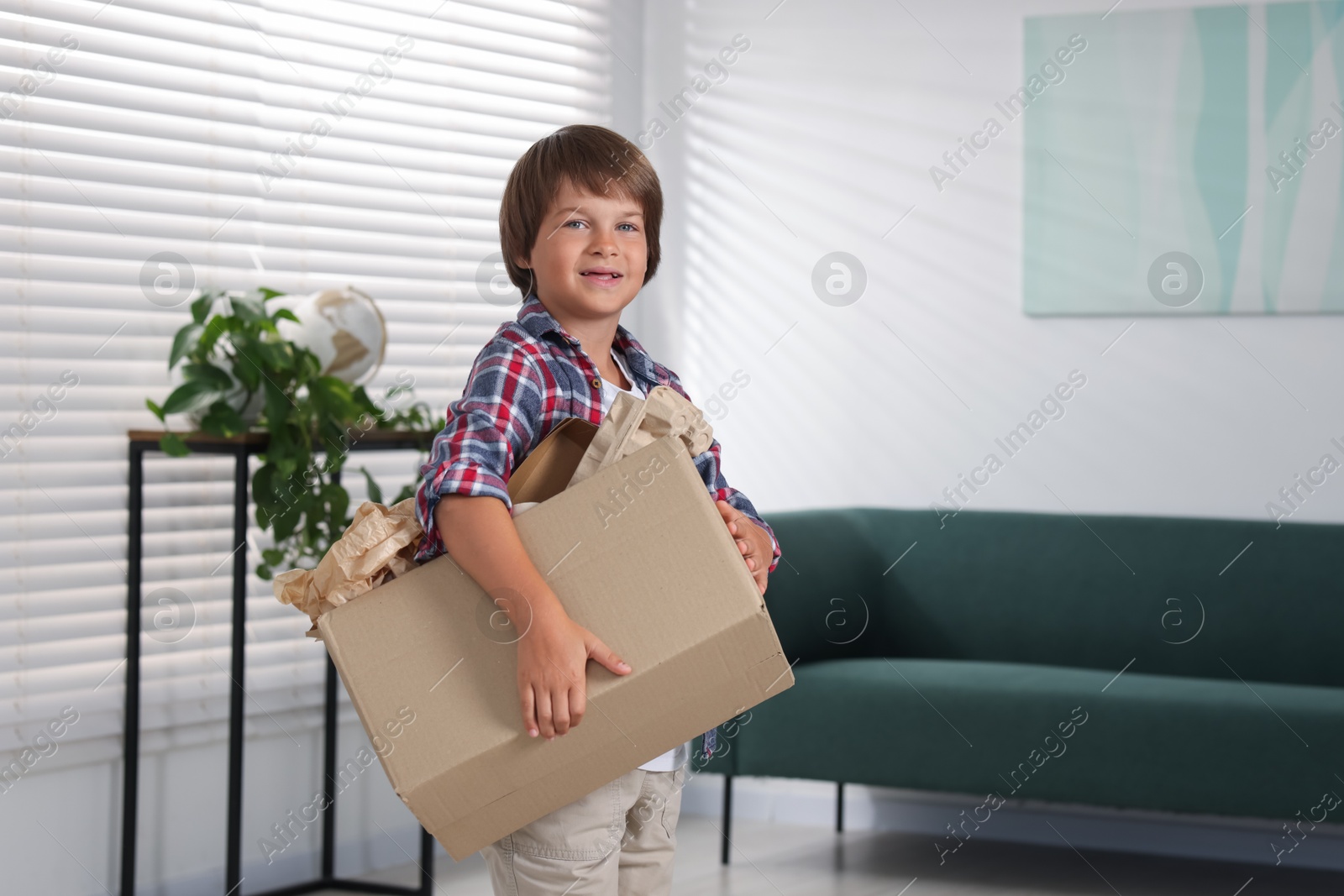 Recycling. Cute little boy with cardboard box full of different waste paper at home, space for text Photo of Recycling. Cute little boy with cardboard box full of different waste paper at home, space for text