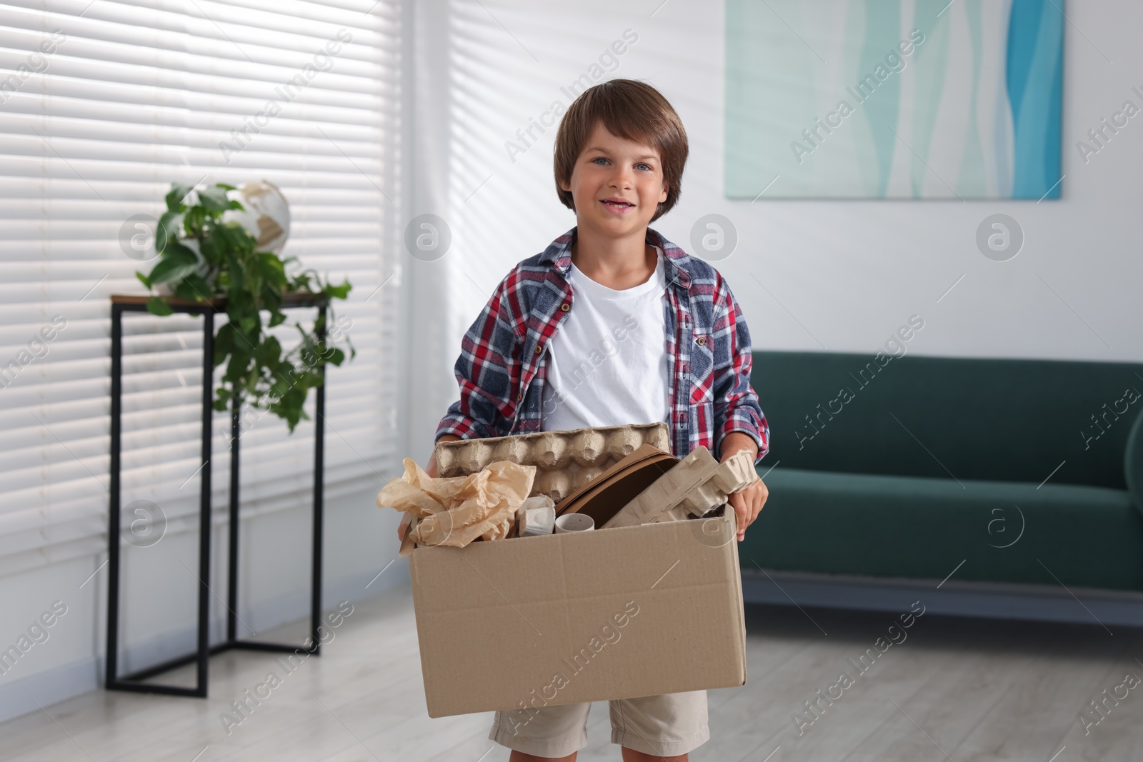 Recycling. Cute little boy with cardboard box full of different waste paper at home Photo of Recycling. Cute little boy with cardboard box full of different waste paper at home