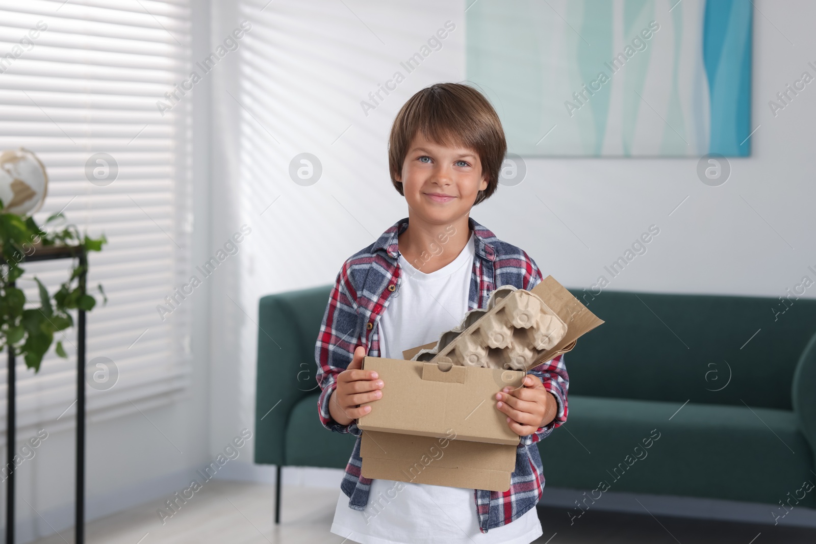 Recycling. Cute little boy with cardboard box full of different waste paper at home Photo of Recycling. Cute little boy with cardboard box full of different waste paper at home