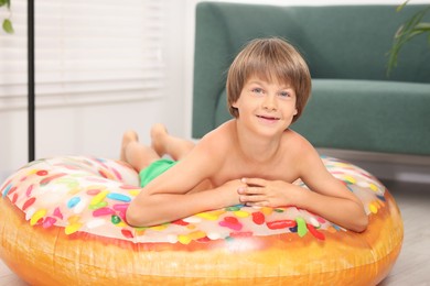 Photo of Dreaming about vacation at sea. Little boy on inflatable ring indoors