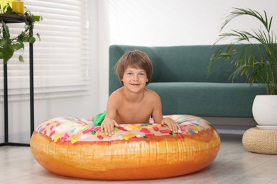 Photo of Dreaming about vacation at sea. Little boy on inflatable ring indoors