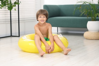 Photo of Dreaming about vacation at sea. Little boy with inflatable ring on floor indoors
