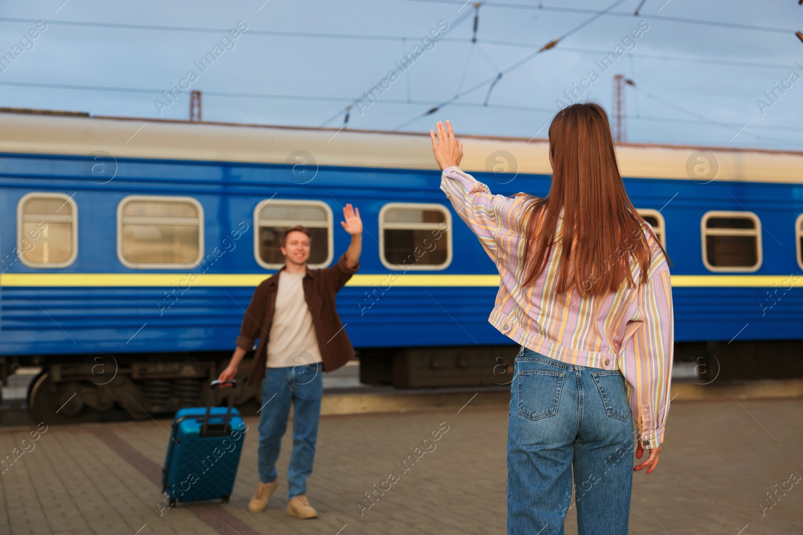 Photo of Goodbye. Woman waving to her boyfriend on platform of railway station, selective focus