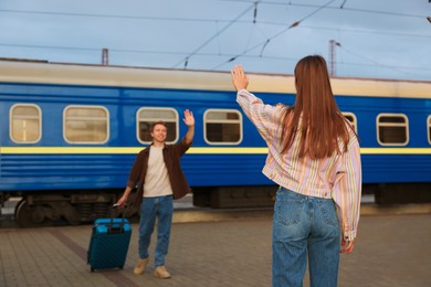 Photo of Goodbye. Woman waving to her boyfriend on platform of railway station, selective focus