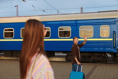 Photo of Goodbye. Woman waving to her boyfriend on platform of railway station, selective focus