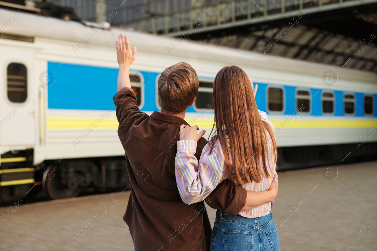 Goodbye. Couple waving on platform of railway station, back view Photo of Goodbye. Couple waving on platform of railway station, back view