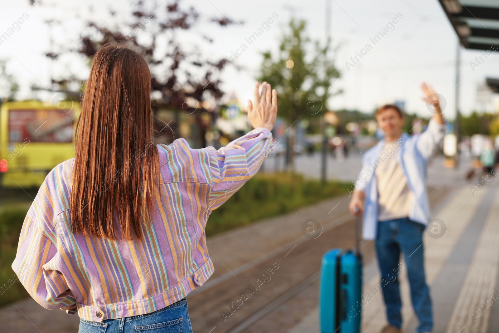 Photo of Goodbye. Woman waving to her boyfriend at bus stop, selective focus