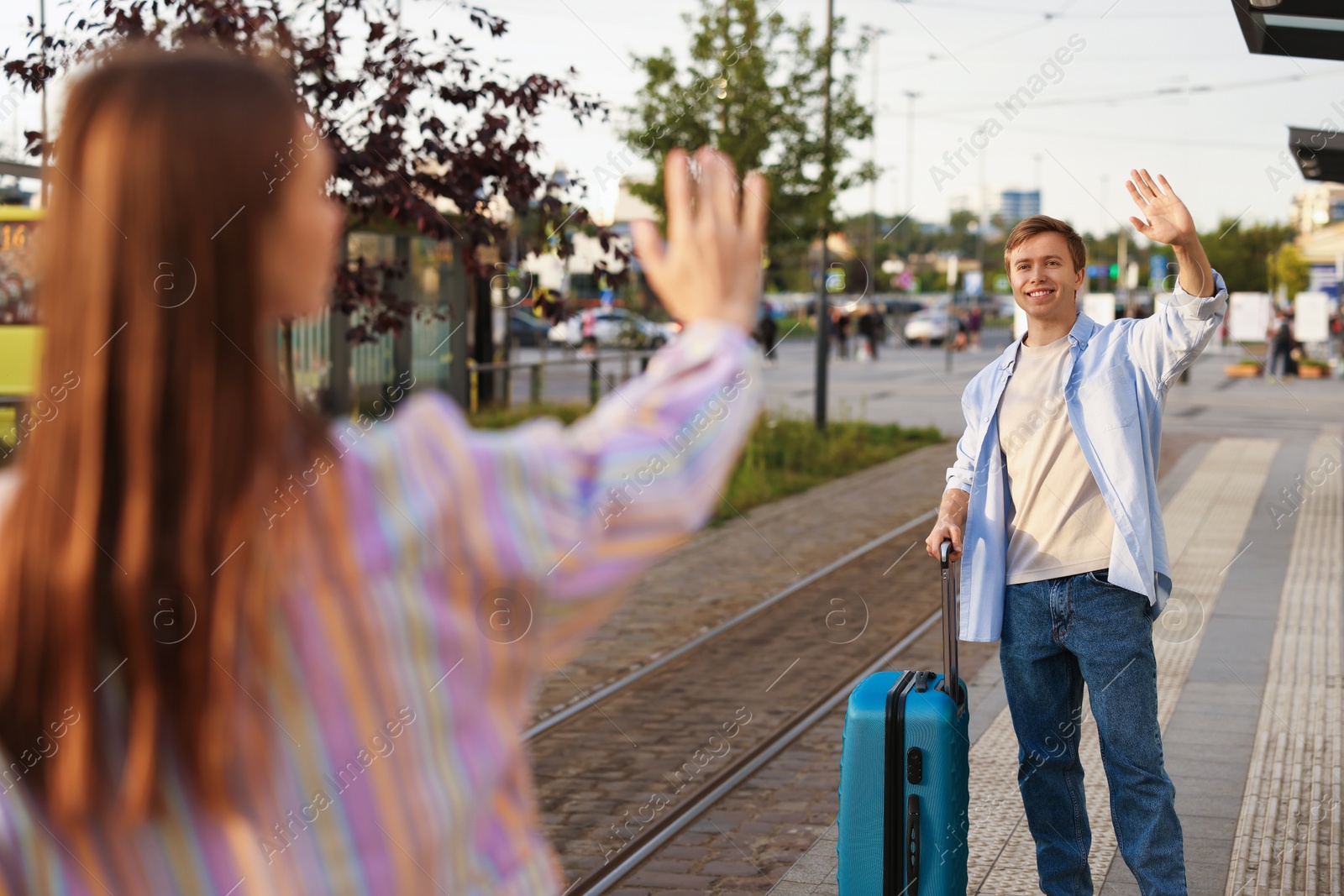 Photo of Goodbye. Woman waving to her boyfriend at bus stop, selective focus