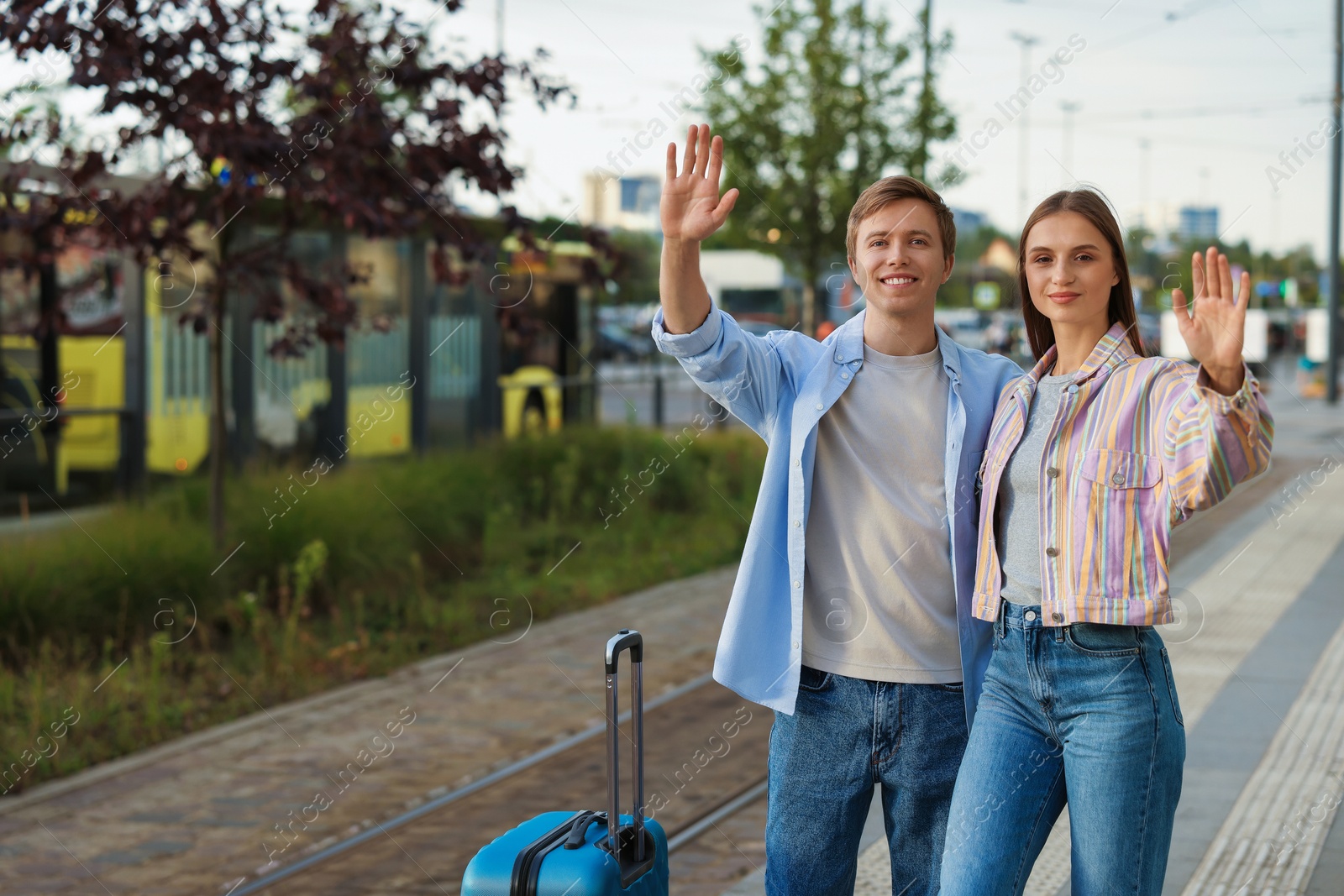 Goodbye. Lovely couple with suitcases waving at bus stop, space for text Photo of Goodbye. Lovely couple with suitcases waving at bus stop, space for text