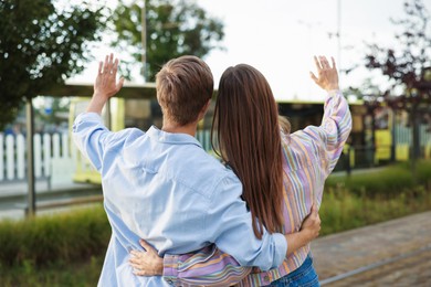 Photo of Goodbye. Lovely couple waving on city street, back view