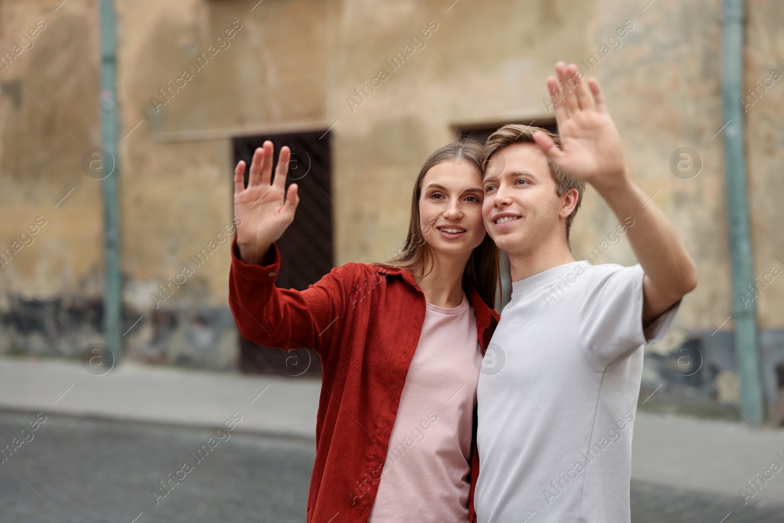 Goodbye. Lovely couple waving on city street, space for text Photo of Goodbye. Lovely couple waving on city street, space for text