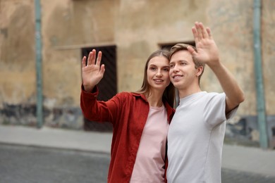 Photo of Goodbye. Lovely couple waving on city street, space for text