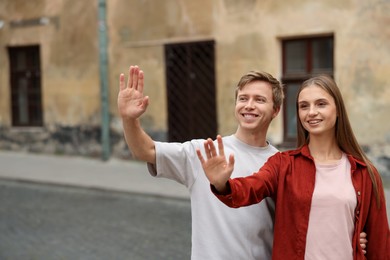 Photo of Goodbye. Lovely couple waving on city street, space for text