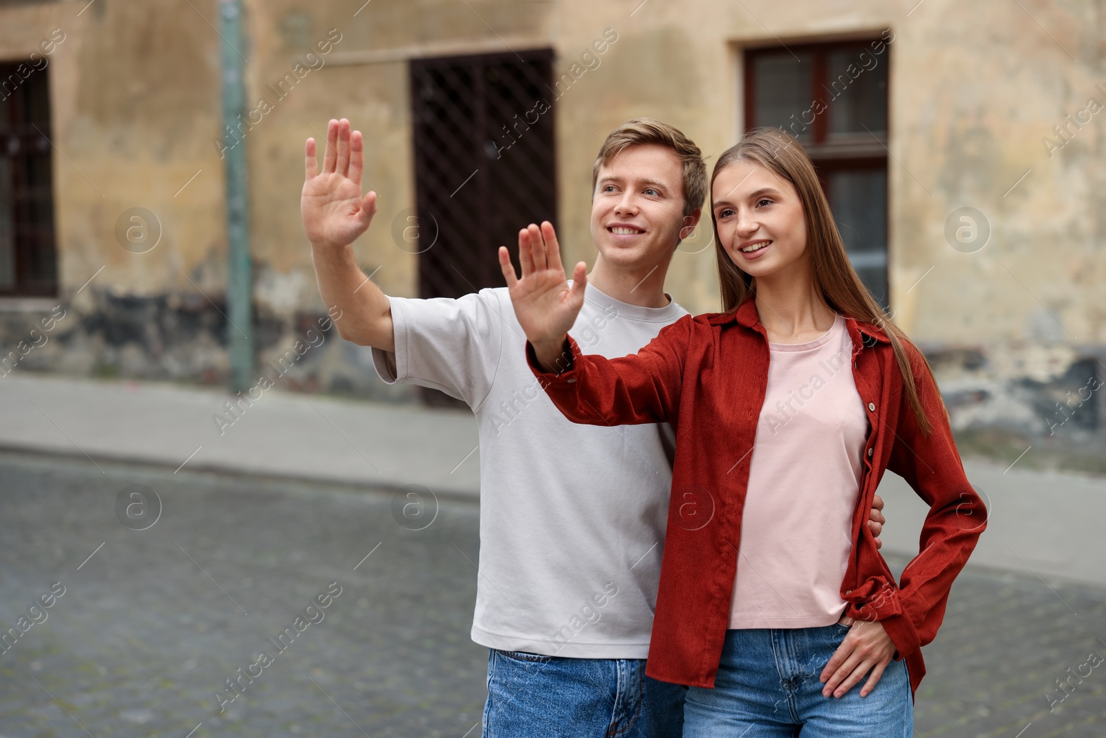 Goodbye. Lovely couple waving on city street, space for text Photo of Goodbye. Lovely couple waving on city street, space for text
