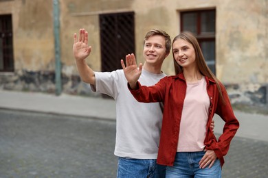 Photo of Goodbye. Lovely couple waving on city street, space for text
